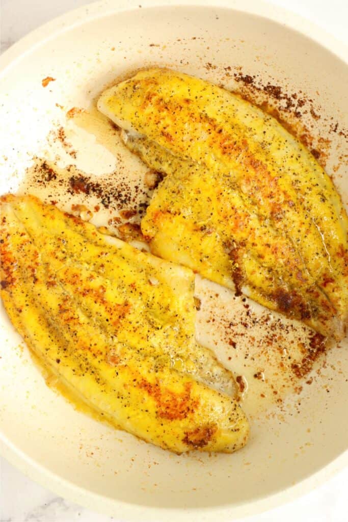 Overhead shot of cooked catfish filets in skillet. 