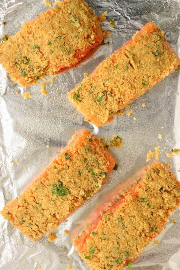 Overhead shot of unbaked herb crusted salmon fillets on baking sheet. 