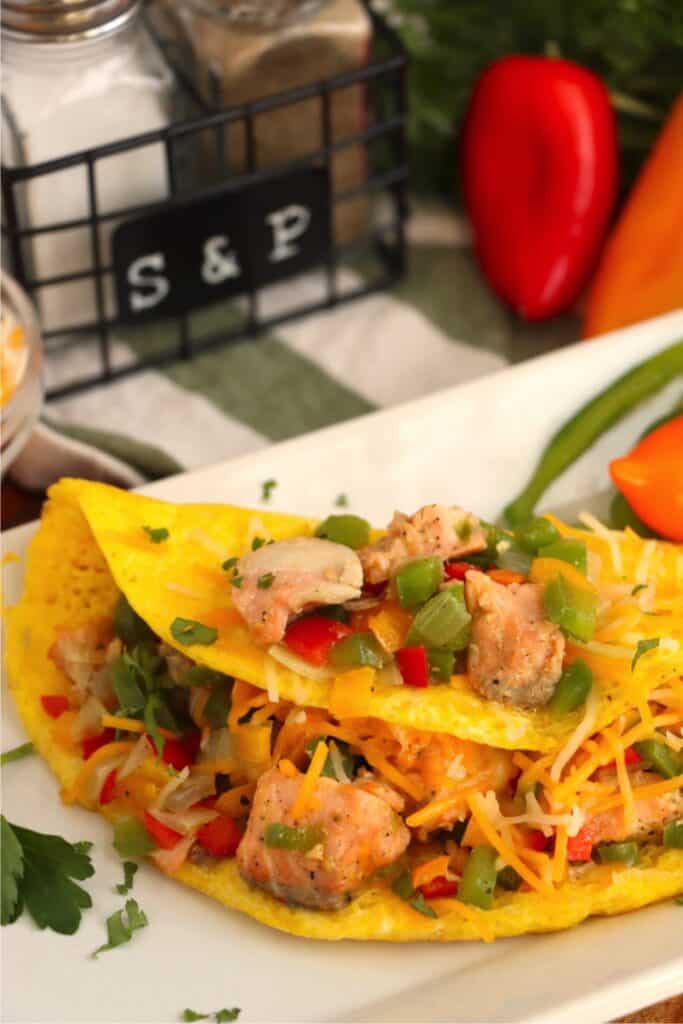 Closeup shot of salmon omelet topped with salmon and veggies on plate.