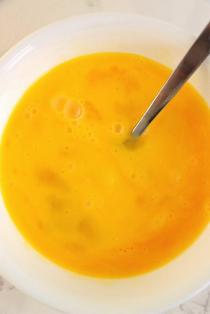 Closeup overhead shot of whisked eggs in bowl