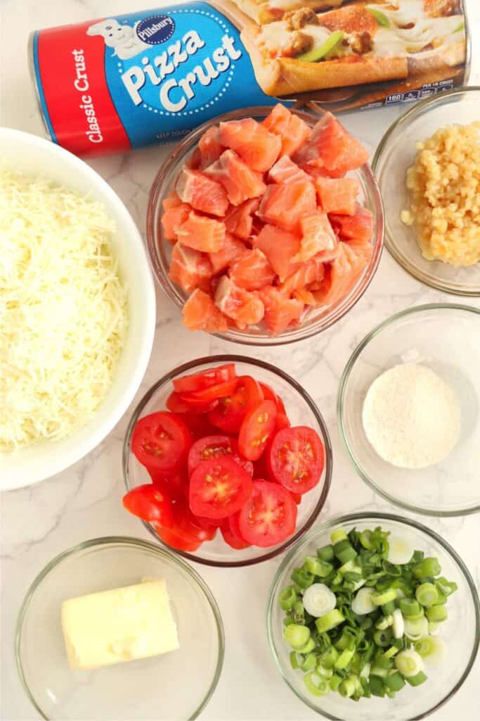 Overhead shot of salmon pizza ingredients on table. 