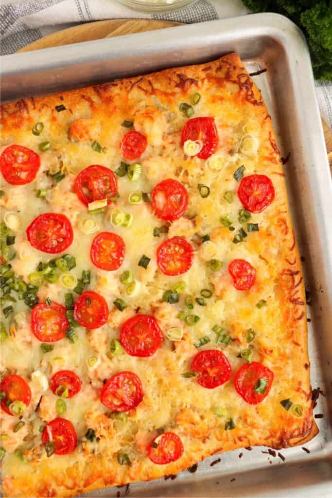 Overhead shot of baked salmon pizza in baking pan. 