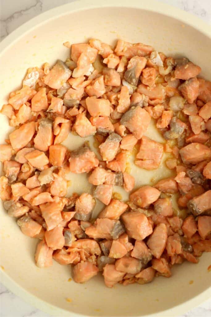 Overhead shot of cooked salmon and minced garlic in skillet. 