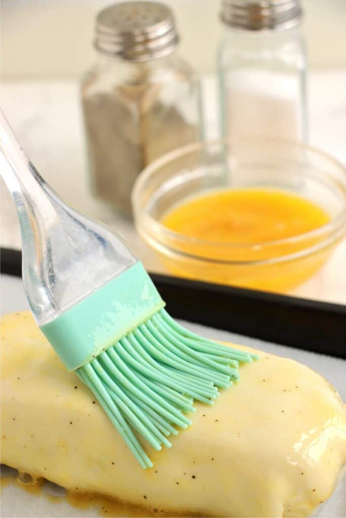 Closeup shot of salmon Wellington being brushed with egg wash. 