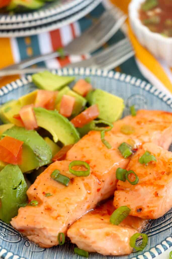 Plateful of sweet chili salmon with sliced avocado.