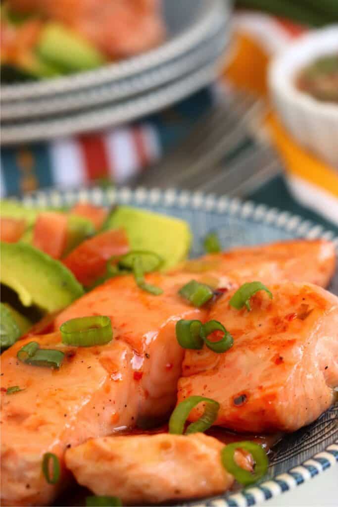 Closeup shot of sweet chili salmon with avocado on plate. 