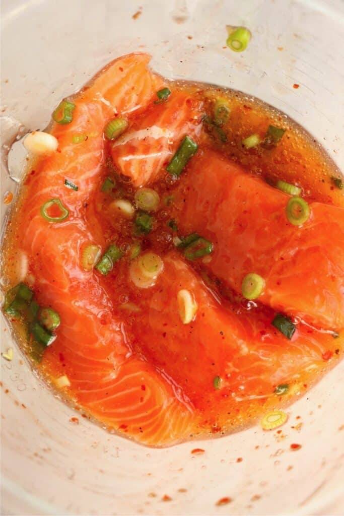 Overhead shot of salmon fillet slices miarnating in sweet chili sauce.