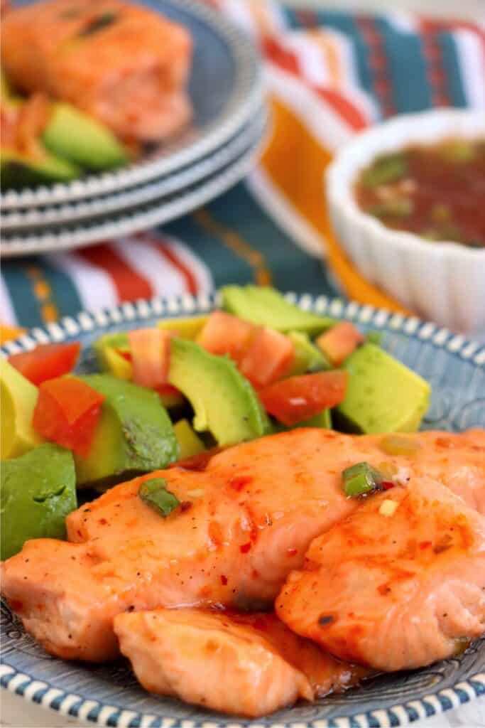 Closeup shot of sweet chili salmon fillets with slice avocado on plate. 