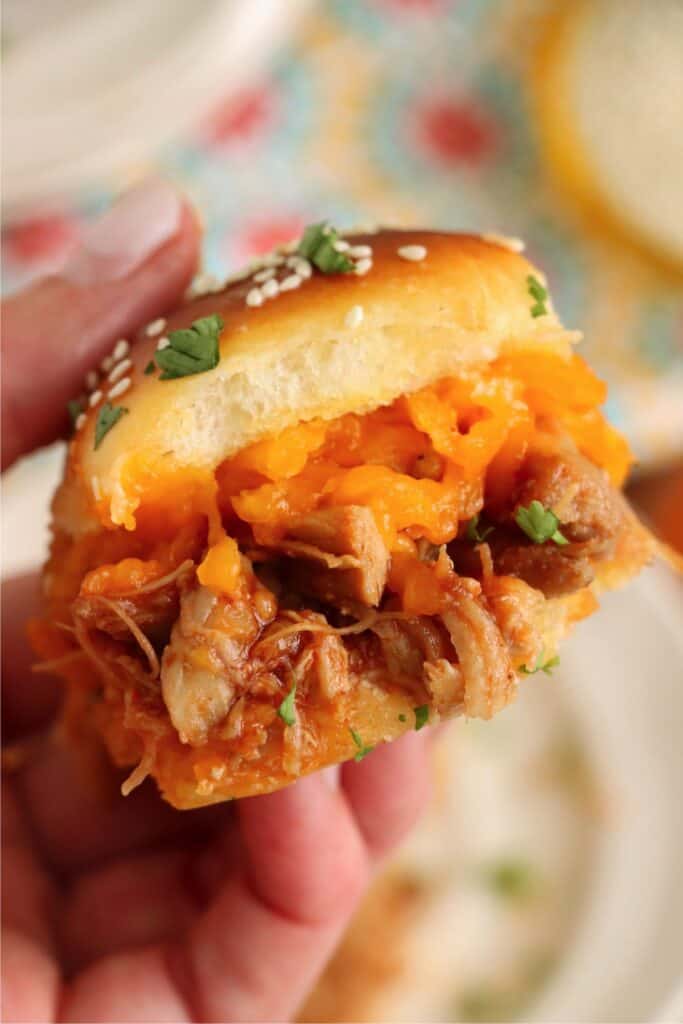 Closeup shot of hand holding a BBQ chicken slider.