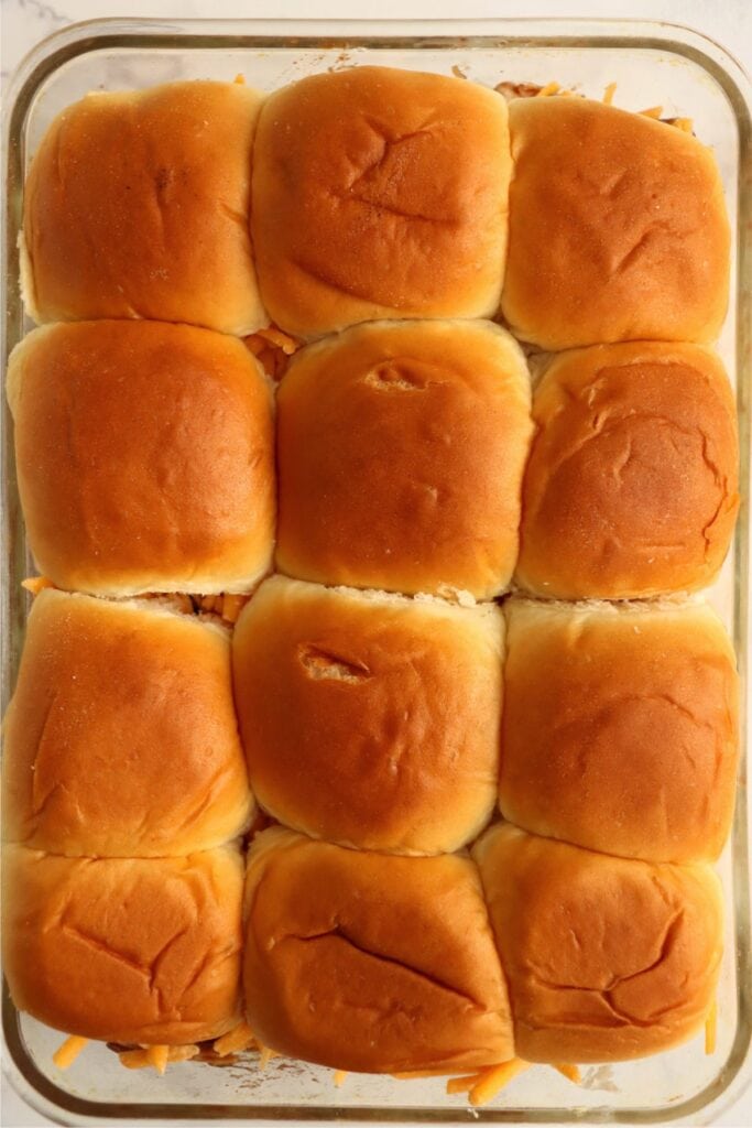 Overhead shot of unbaked BBQ chicken sliders in baking dish.