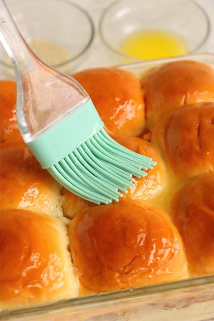 Closeup shot of BBQ chicken sliders being brushed with melted butter. 