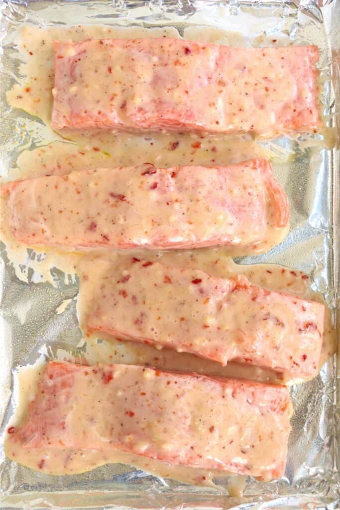 Overhead shot of unbaked salmon filets coated in mayo marinade. 