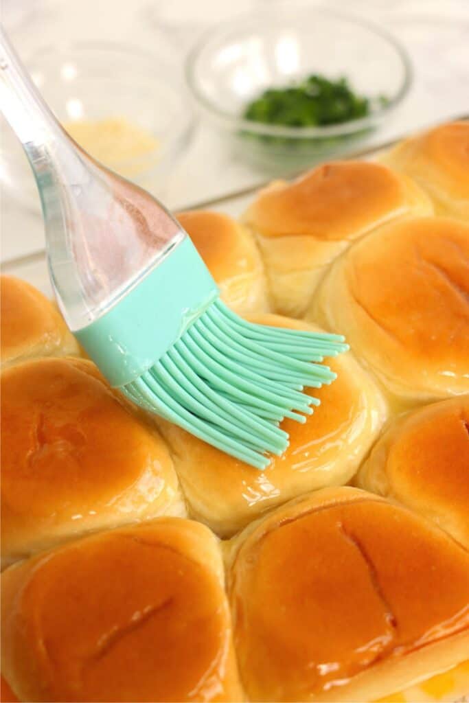 Closeup shot of sliders being brushed with melted butter. 