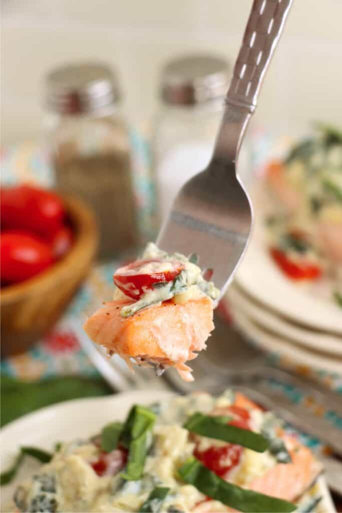 Closeup shot of forkful of salmon florentine. 