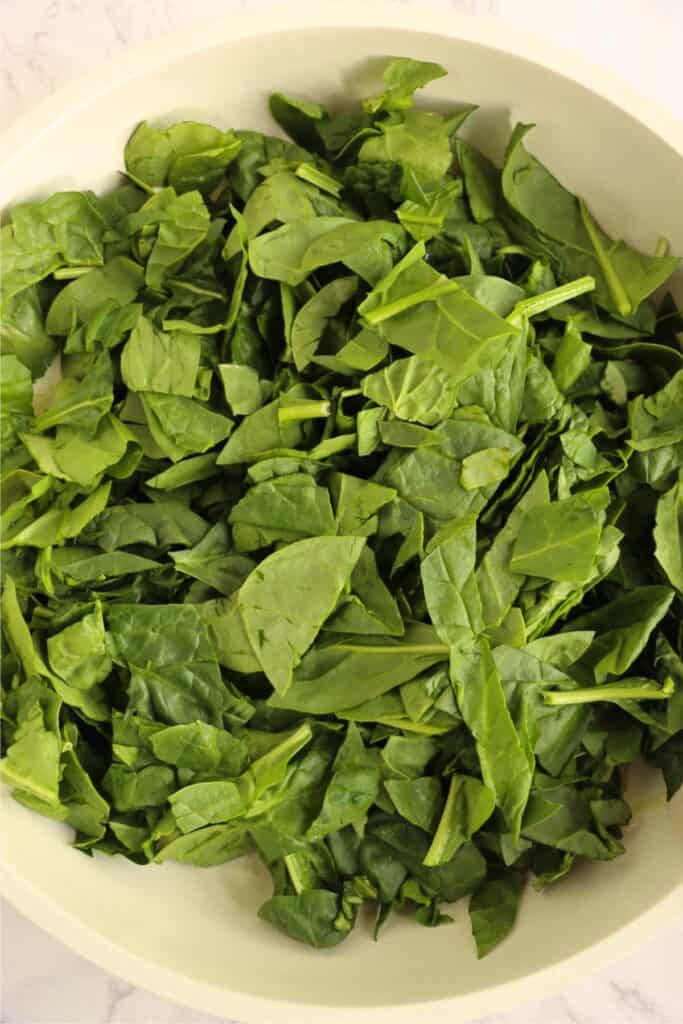 Closeup overhead shot of raw spinach in skillet. 