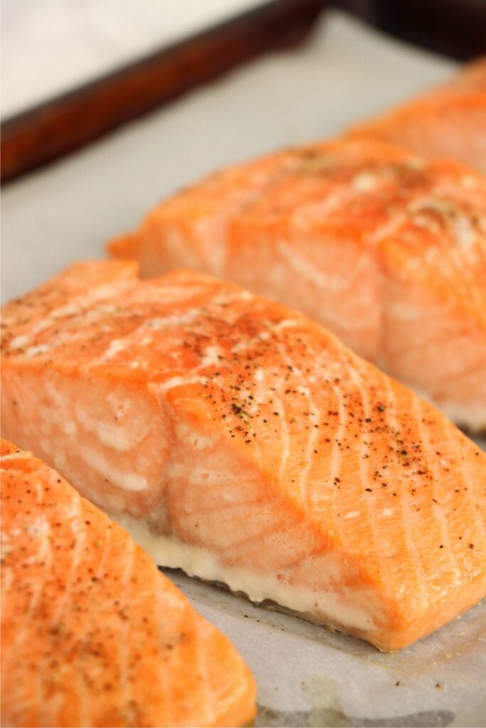 Closeup shot of baked salmon filets on baking sheet. 