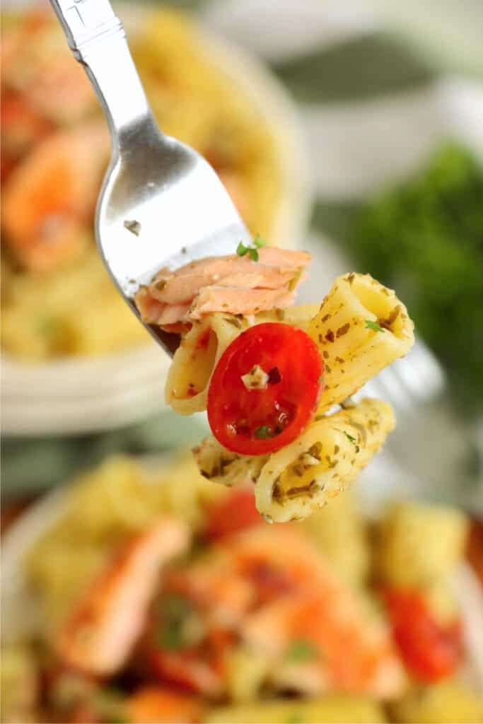 Closeup shot of forkful of salmon and pesto pasta. 