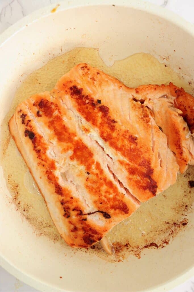 Overhead shot of cooked salmon filet in skillet. 