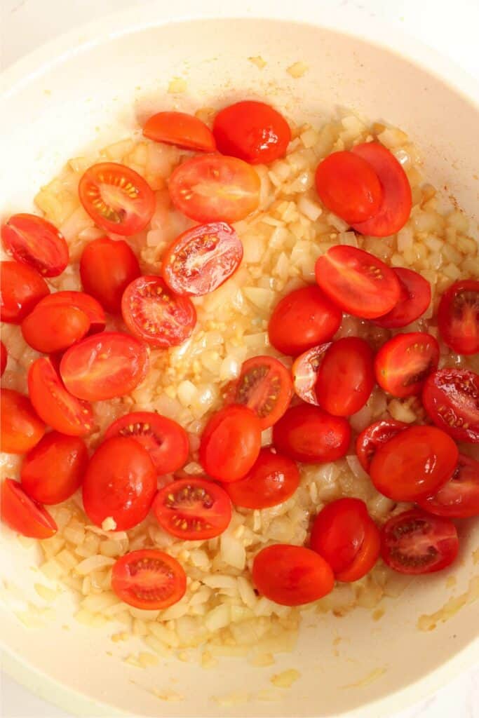 Overhead shot of onions, garlic, and tomatoes in skillet. 