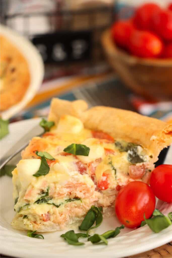 Closeup shot of slice of spinach salmon quiche on plate. 