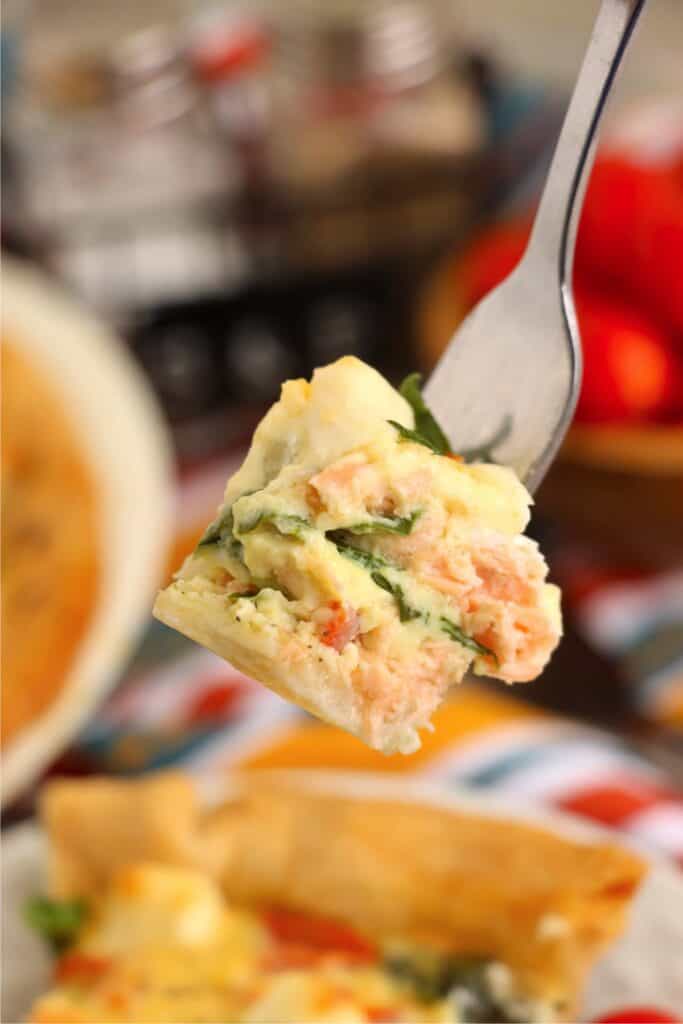 Closeup shot of forkful of spinach salmon quiche. 