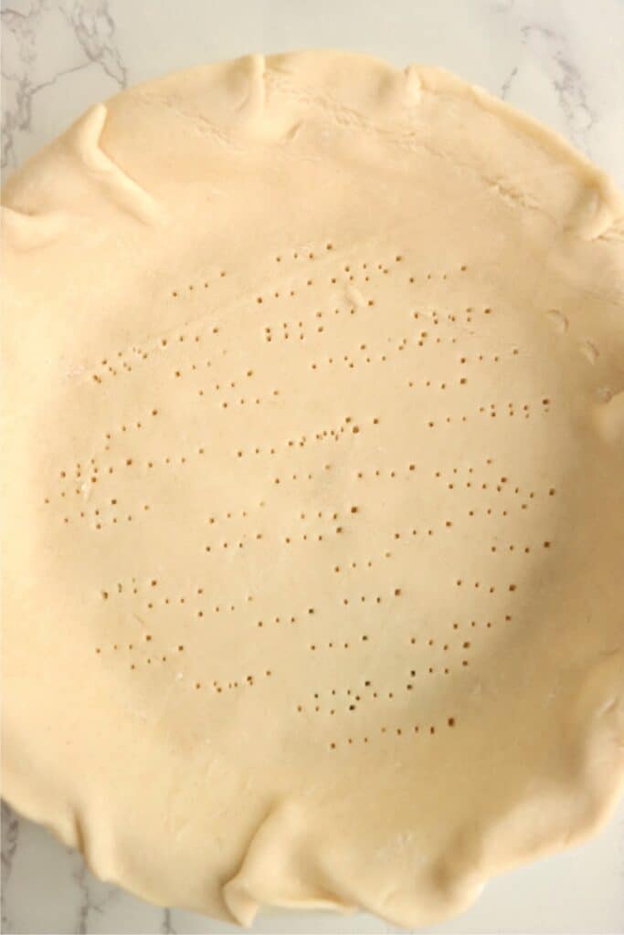 Overhead shot of pie crust with poked holes all over it. 