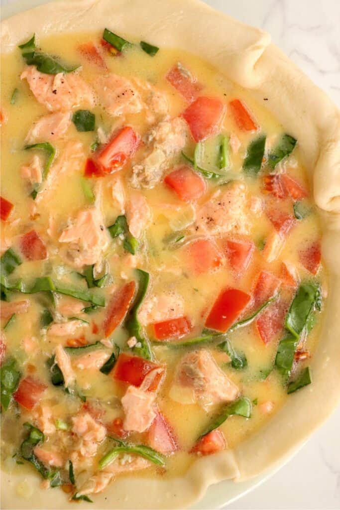 Overhead shot of uncooked spinach salmon quiche. 