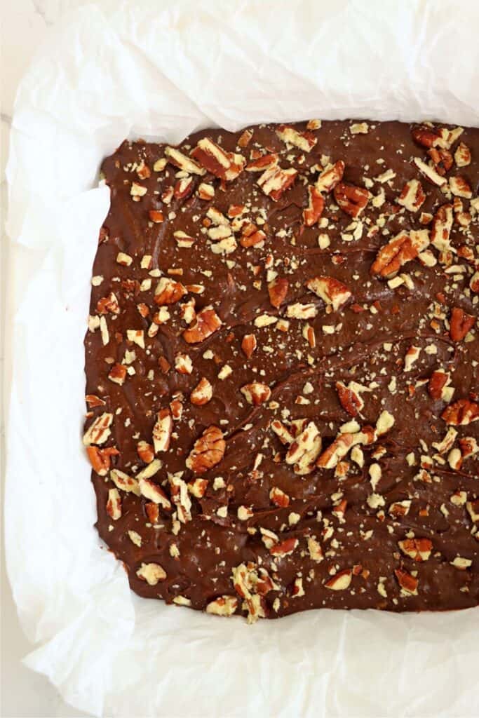 Overhead shot of baking dish with brownie batter topped with pecans