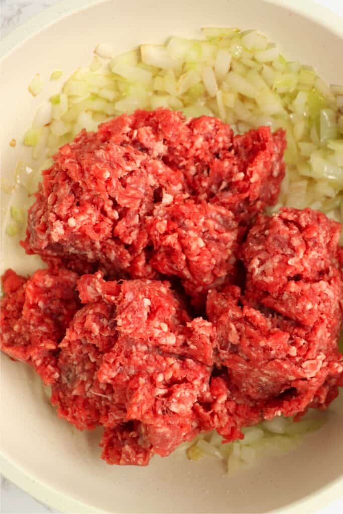 Overhead shot of raw ground beef in skillet with onions. 