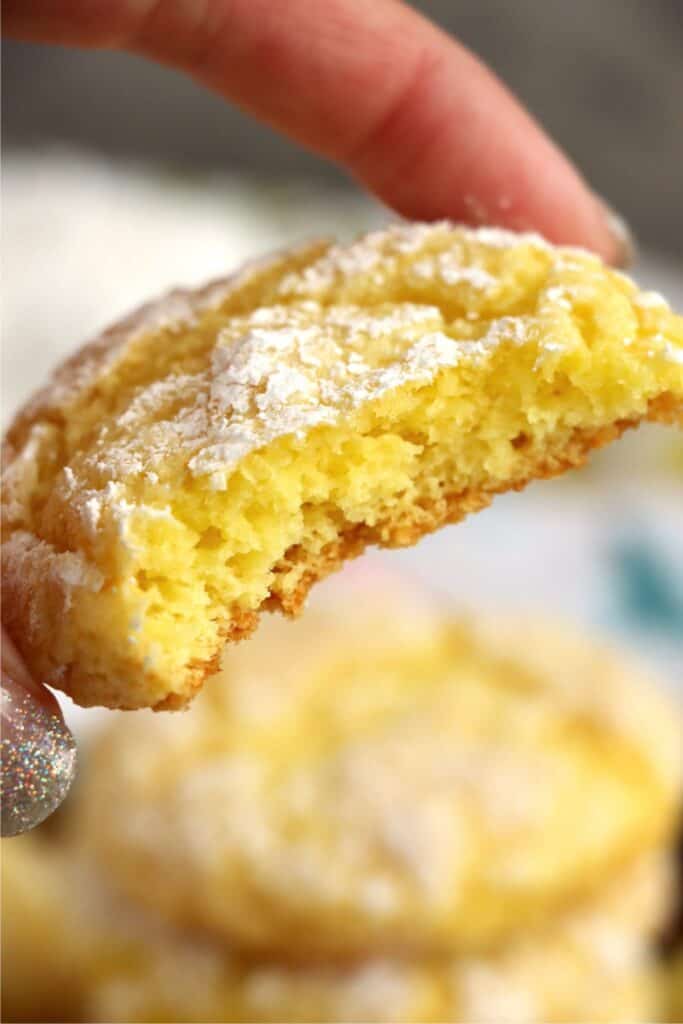Closeup shot of hand holding a lemon cake mix cookie with bite taken out.