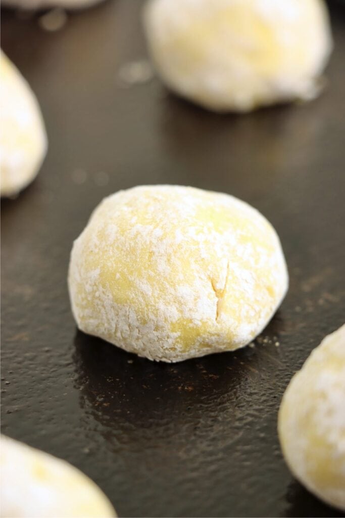 Closeup shot of lemon cake mix cookie dough ball coated with powdered sugar. 