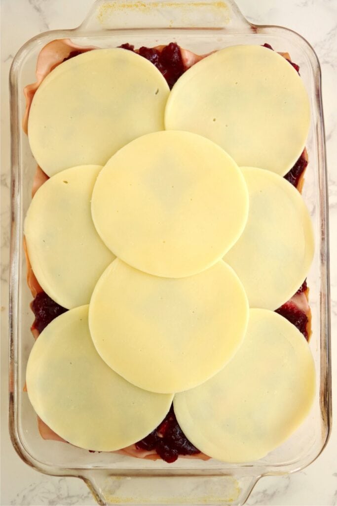 Overhead shot of turkey sliders topped with cranberry sauce and provolone slices.