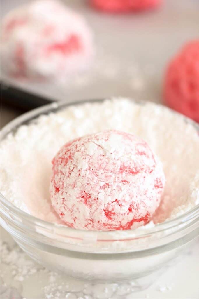Closeup shot of cookie dough ball in dish of powdered sugar.