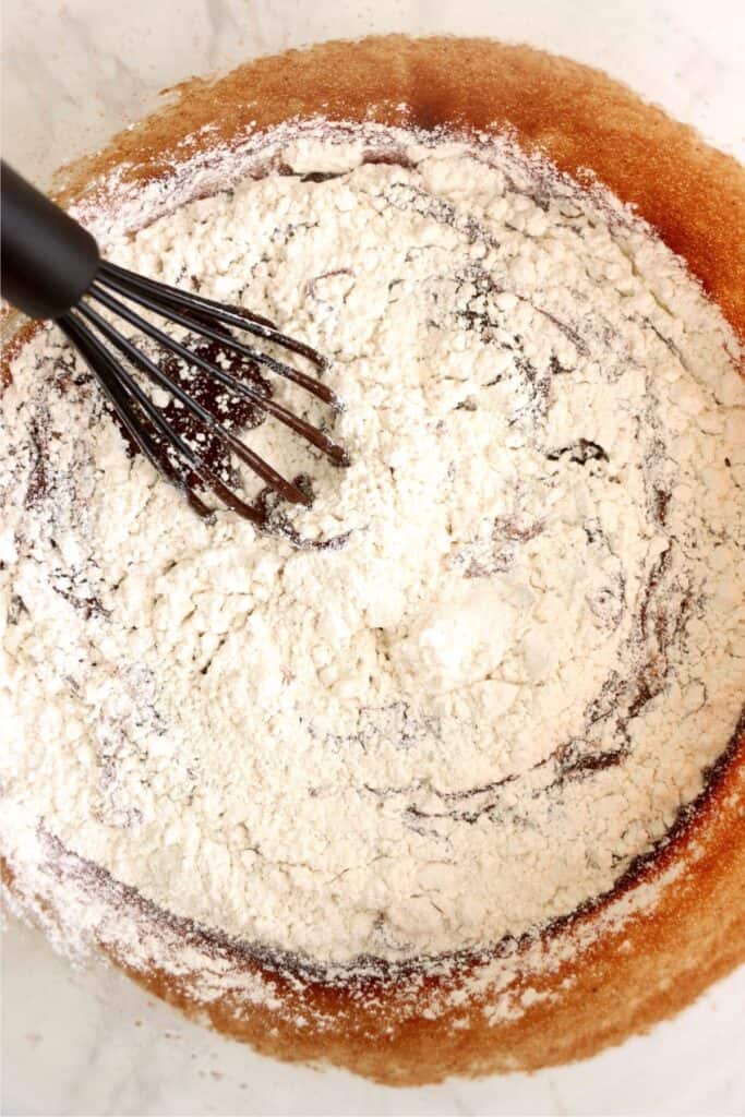 Overhead shot of mixing bowl with flour on top of wet brownie ingredients. 