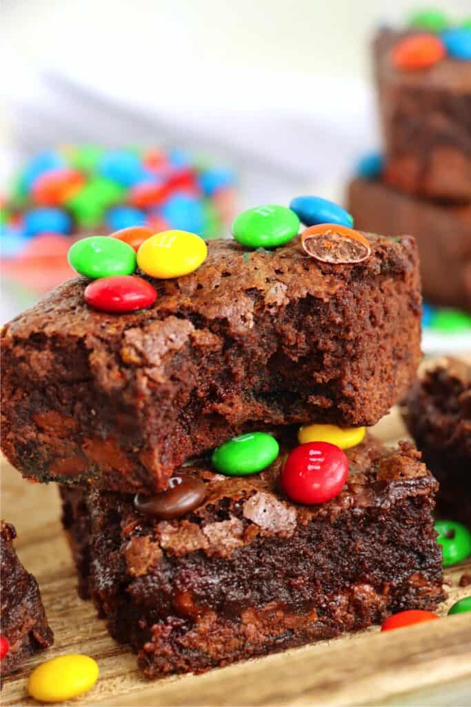 Closeup shot of two M&M brownies stacked atop one another with bite taken out of top brownie.