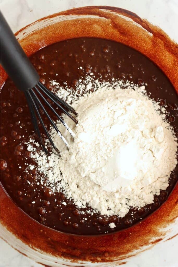 Overhead shot of flour in bowlful of wet brownie ingredients.