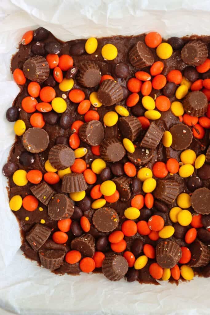 Overhead shot of brownie batter topped with Reese's Pieces and Reese's baking cups.