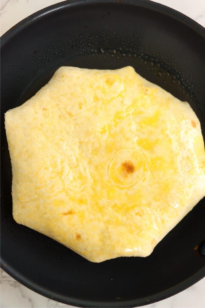 Overhead shot of crunch wrap in skillet. 
