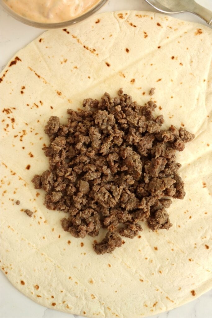 Overhead shot of ground beef on a tortilla shell. 