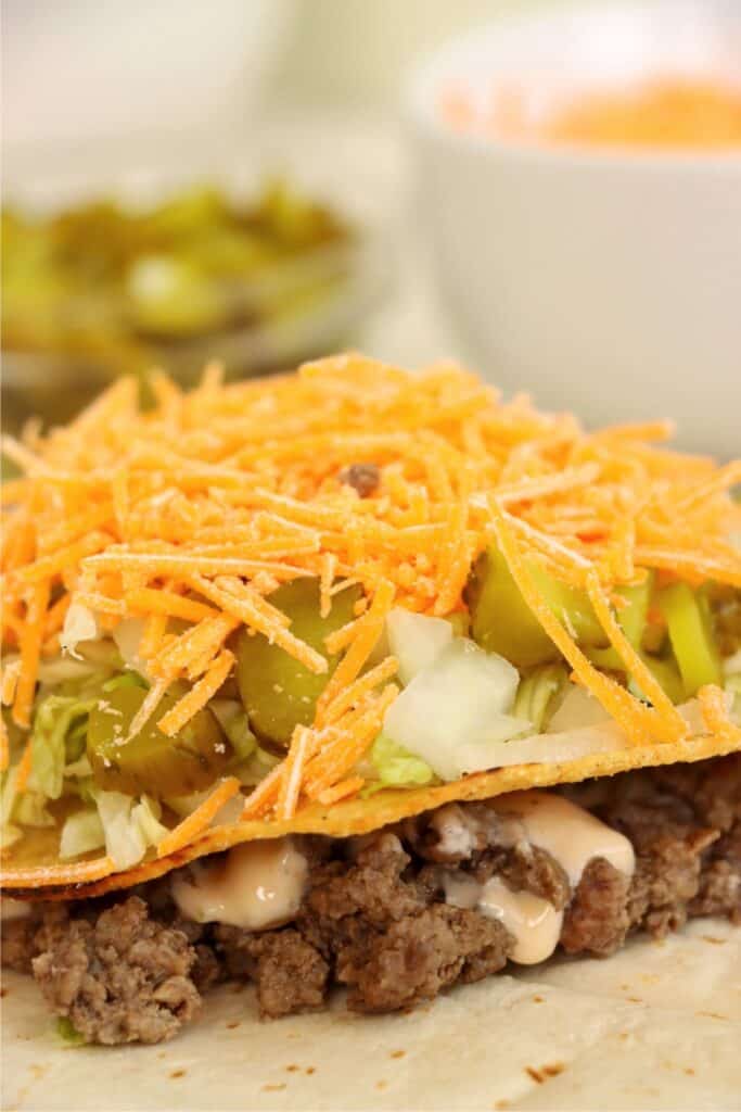 Closeup shto of layered Big Mac crunch wrap filling ingredients. 