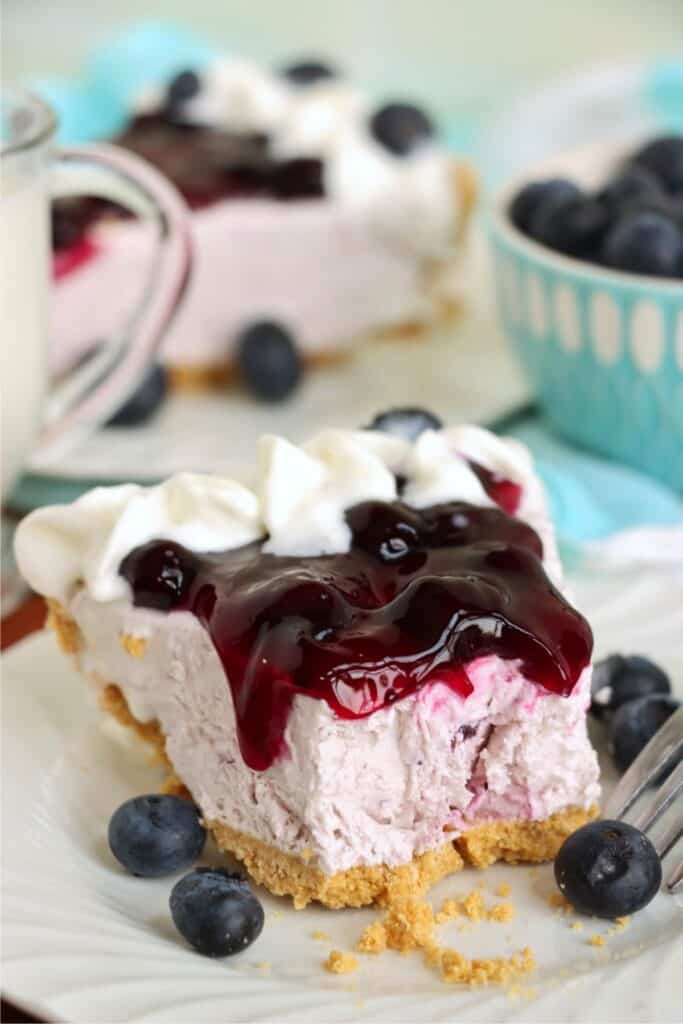 Closeup shot of slice of blueberry cream cheese pie with bite taken out.