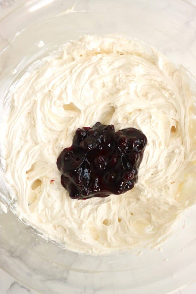 Closeup shot of cream cheese and whipped cream mixture with blueberry pie filling on top. 