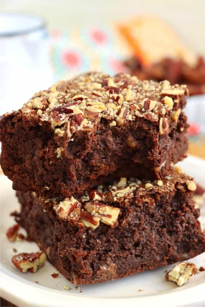 Closeup shot of two brownies stacked atop one another with bite taken out of top brownie.