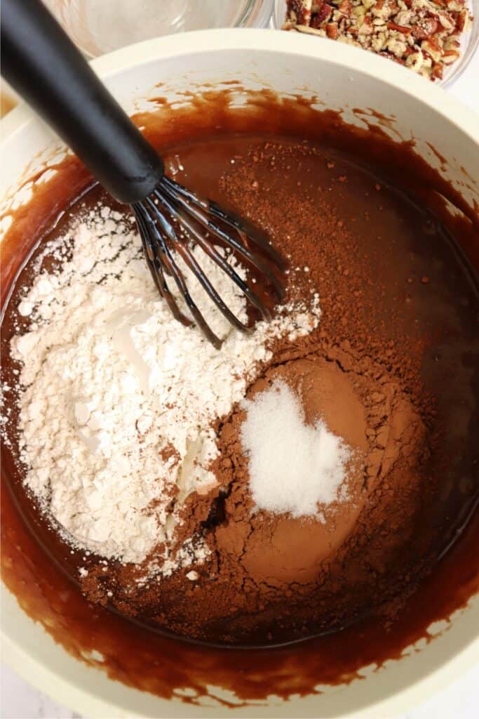 Overhead shot of melted butter mixture with dry brownie ingredients. 