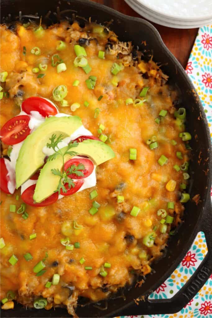 Overhead shot of Mexican chicken and rice casserole garnished with sour cream and avocado slices. 