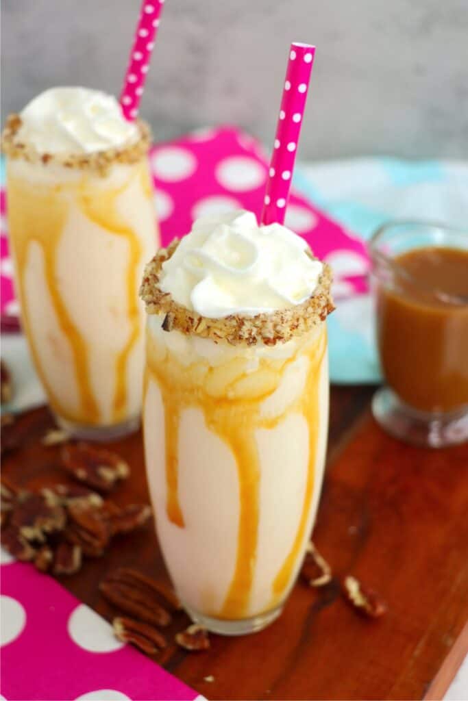 Two glasses with milkshakes on table.