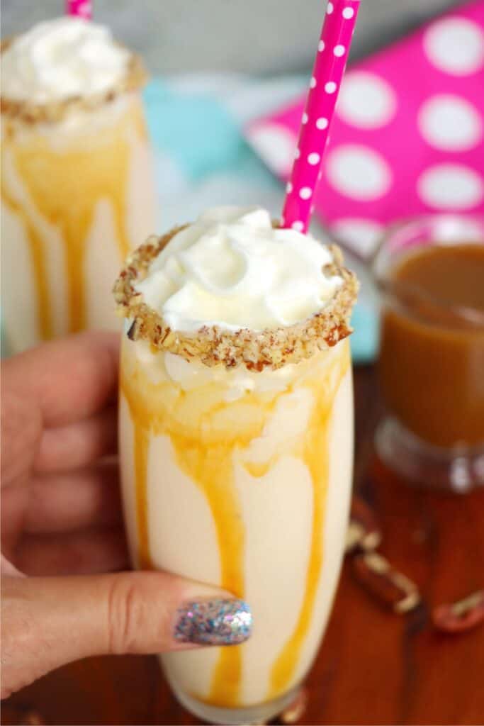 Hand holding a glass of salted caramel milkshake. 