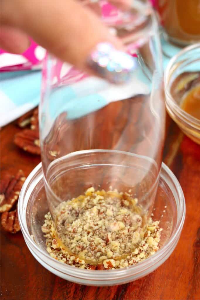 Glass rim being dipped in crushed pecans. 